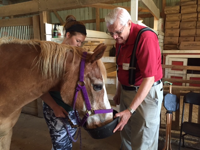 Photo of a horse being fed by senior citizens in the barn at Nature's Edge